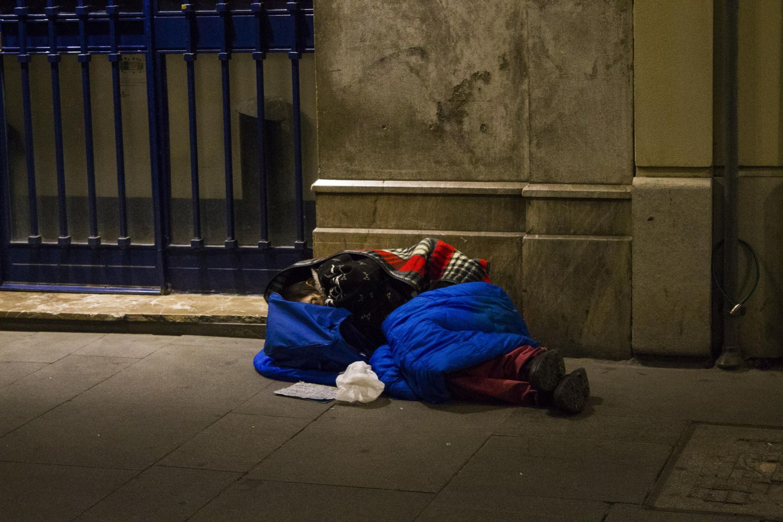 Un 'sin techo' duerme en la calle liado entre mantas.