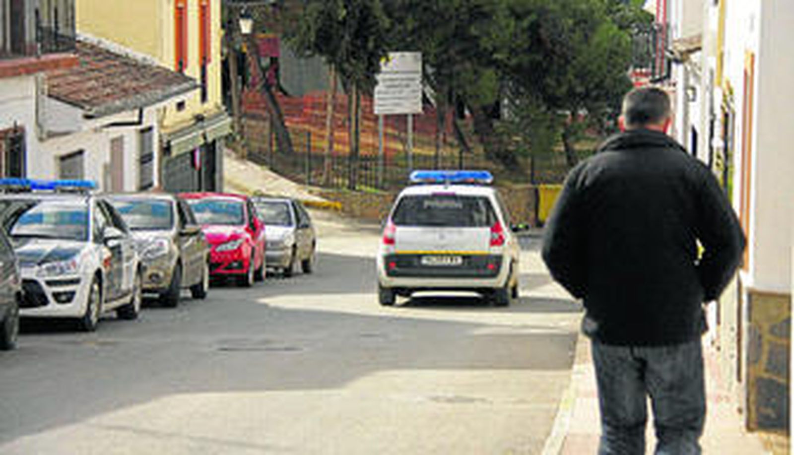 Un hombre camina, ayer, por una de las calles de Arriate ante la presencia de un vehículo de la Policía Local.