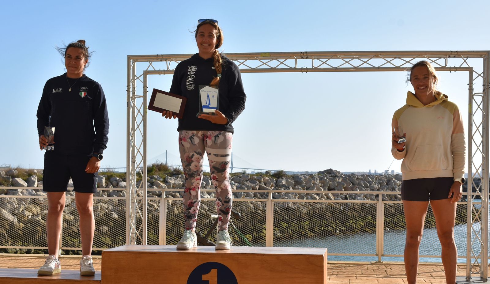 Pilar Lamadrid sonríe en lo más alto del podio tras su título en iQFoil en la Semana Olímpica Andaluza.