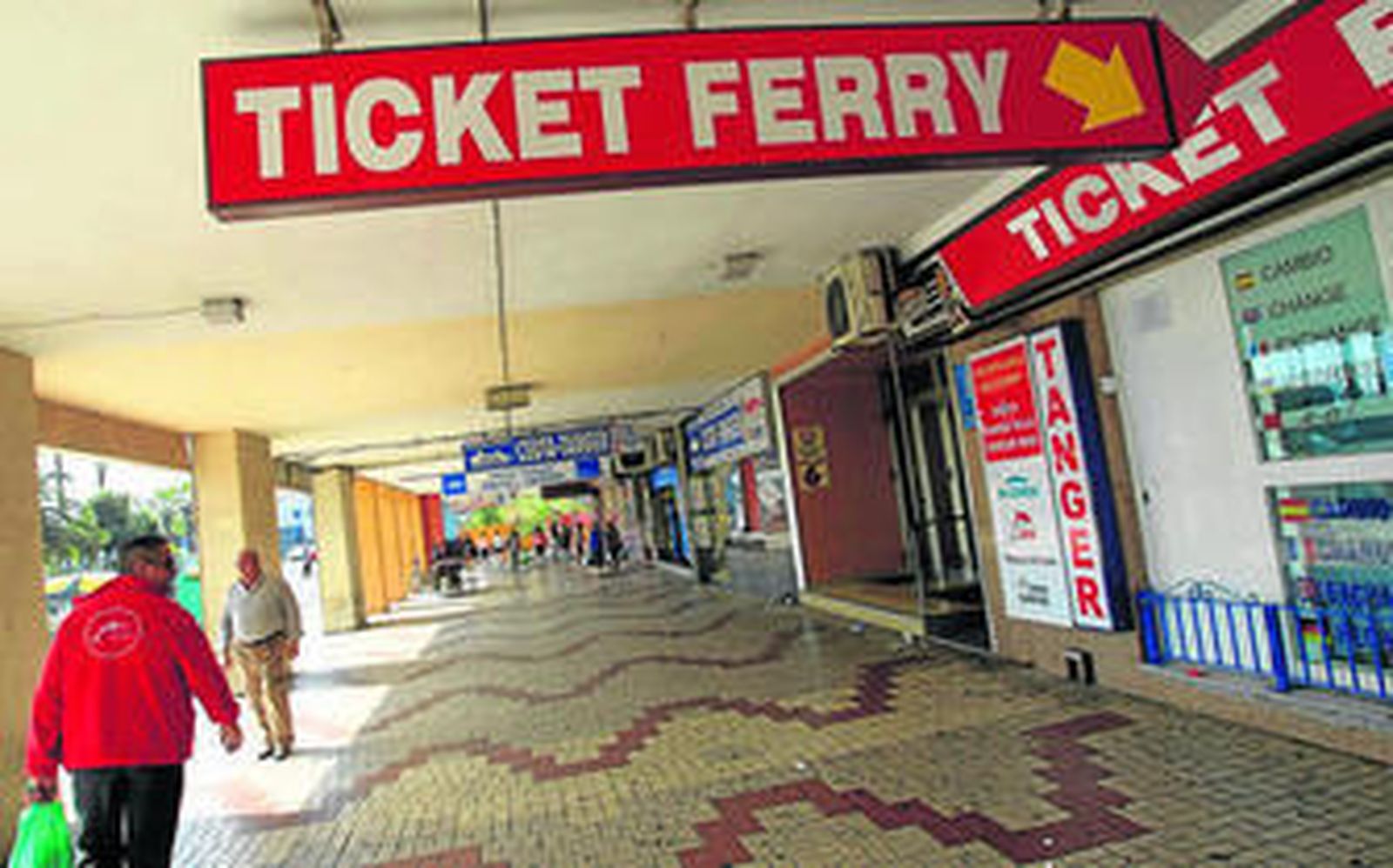 Varias personas pasean por los bajos de un edificio de la Avenida de la Marina de Algeciras lleno de agencias para la venta de billetes de ferris, ayer.