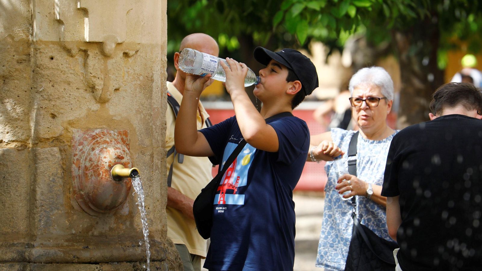 Turistas beben agua en el Patio de los Naranjos