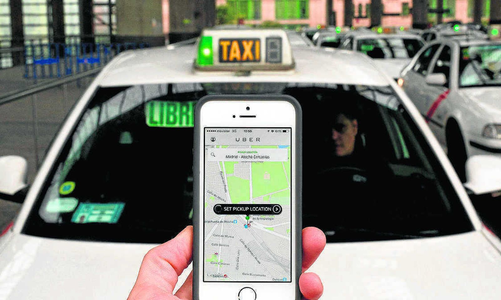 Un usuario consulta la plataforma Uber en su móvil ante un taxi.