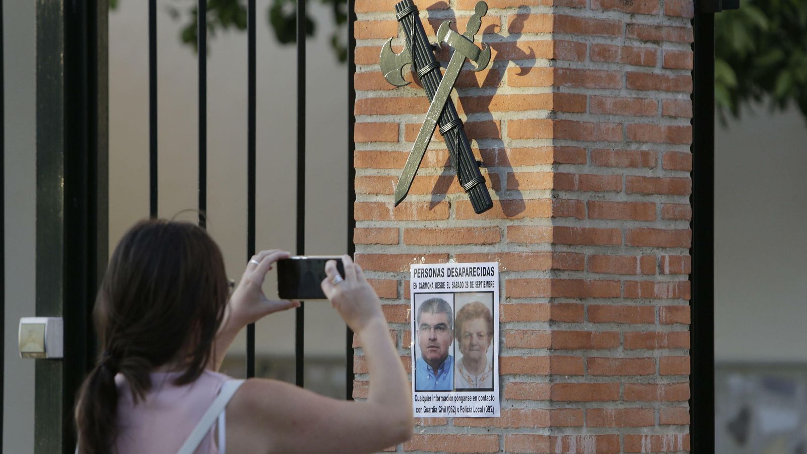 Una mujer fotografía el cartel con los rostros de Juan Antonio y Mercedes.