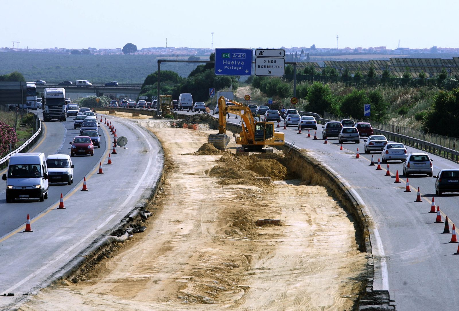 Un operario trabaja con un excavadora en una carretera.