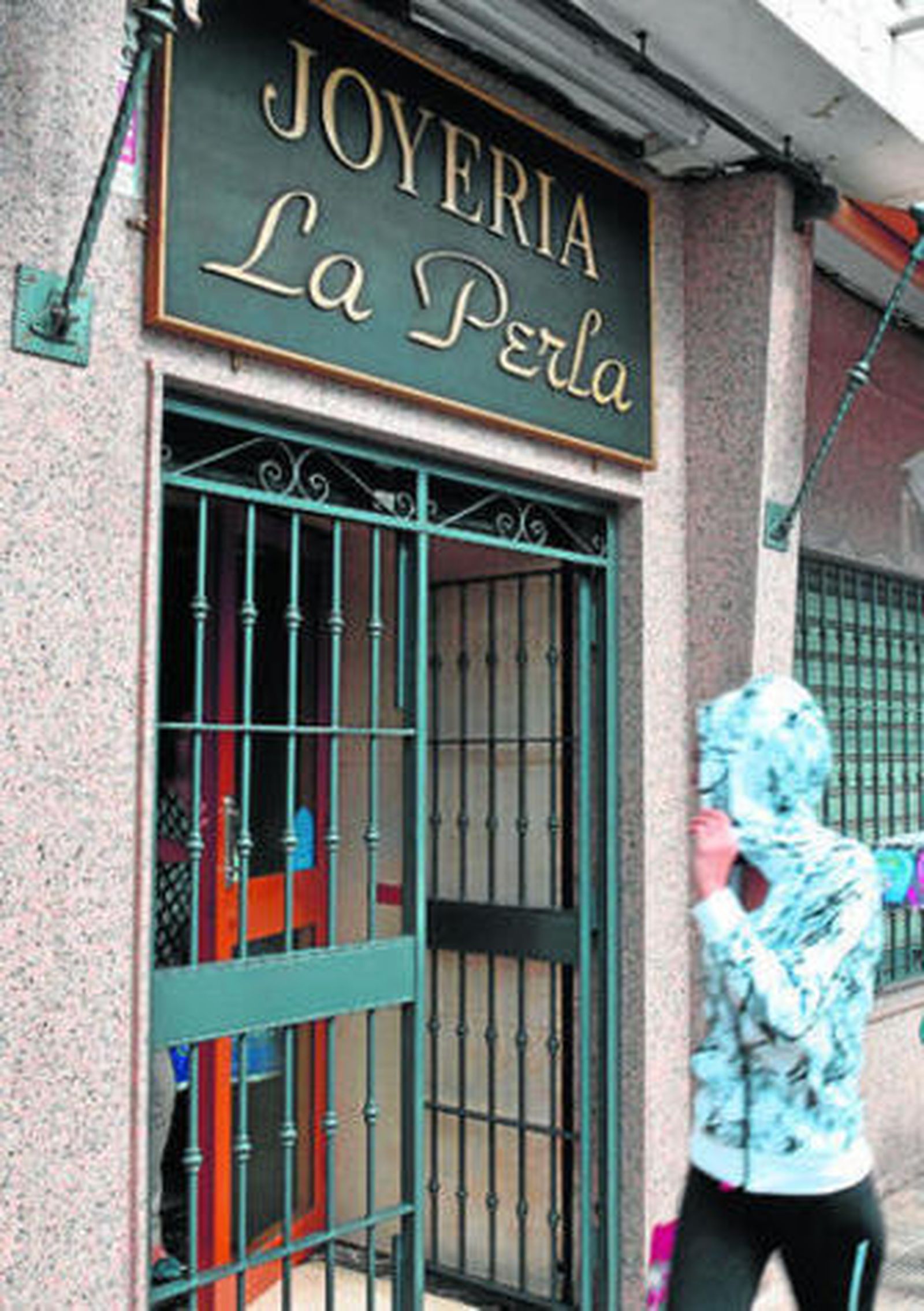 Una joven pasa por delante de la puerta de la joyería La Perla, en cuya puerta ocurrió el robo.