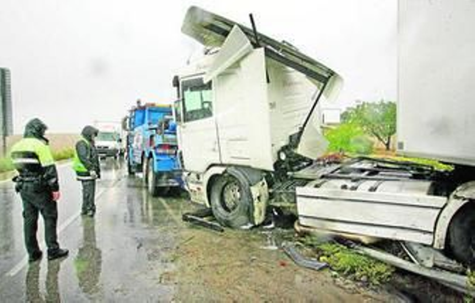 Un policía local contempla las maniobras de la grúa para intentar sacar el camión de la cuneta.