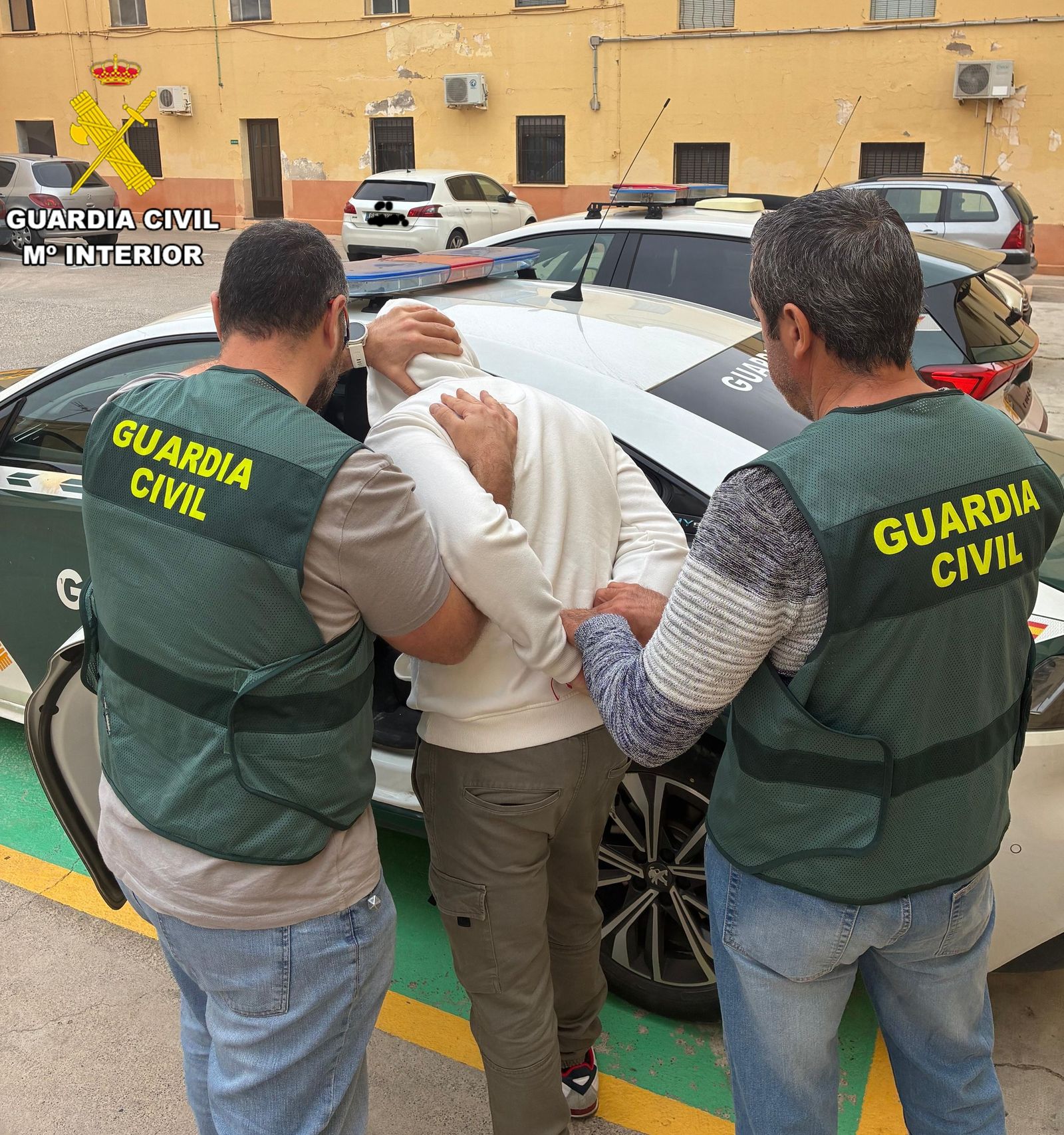 El detenido es introducido por los agentes en un coche patrulla.