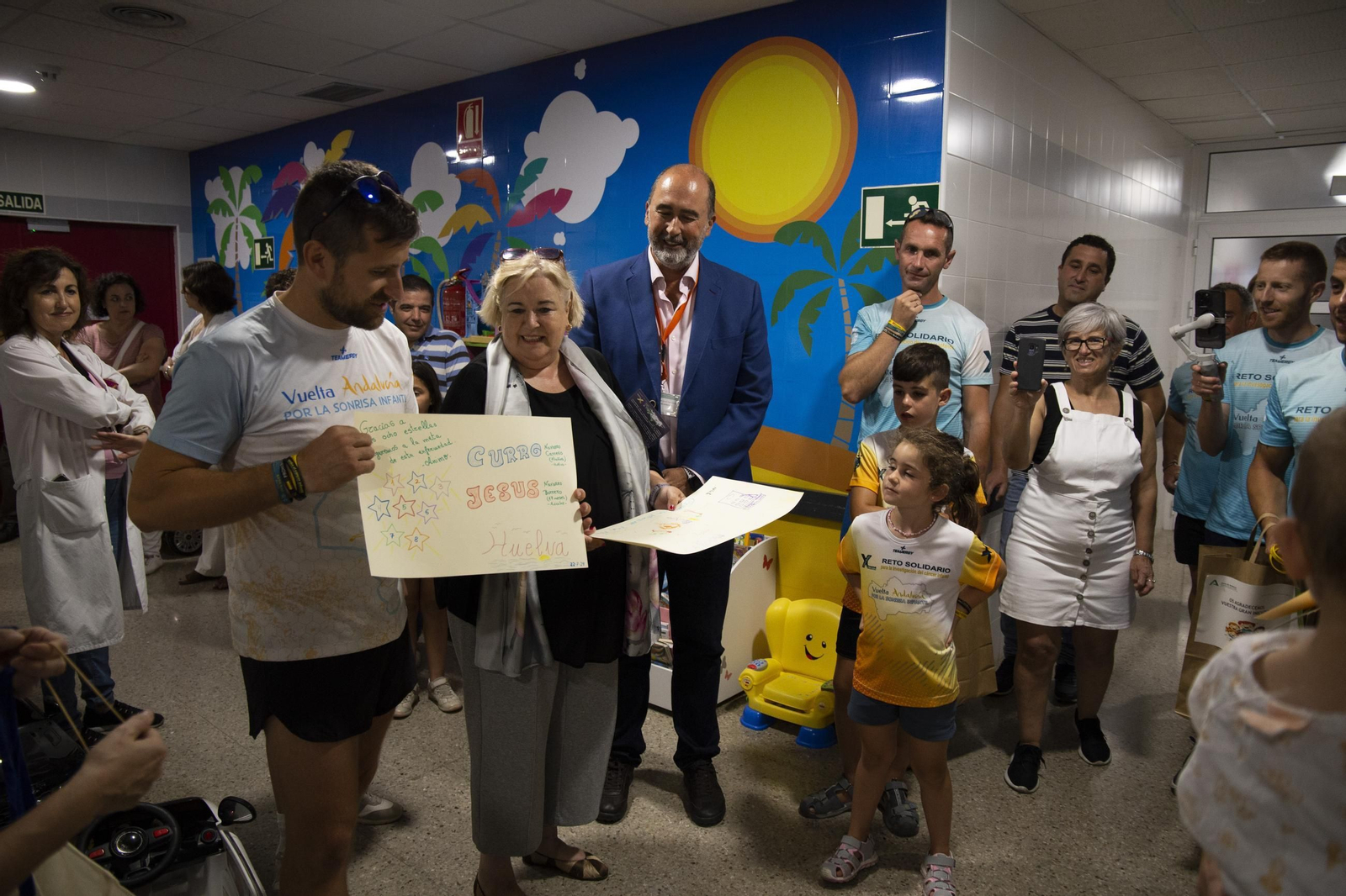 Uno de los atletas junto a Manuela Caro y Manuel García de la Vega, recibiendo un mensaje de apoyo de lo menores ingresados en el Hospital Juan Ramón Jiménez.