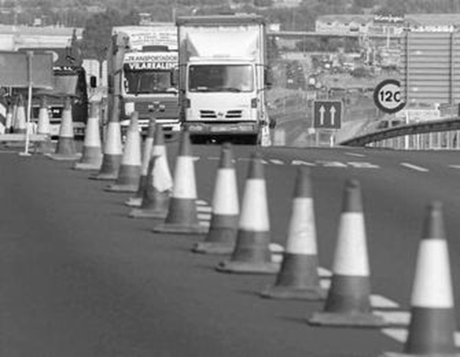 Un grupo de camiones pasa junto al acceso, cerrado, de la autovía de Málaga.