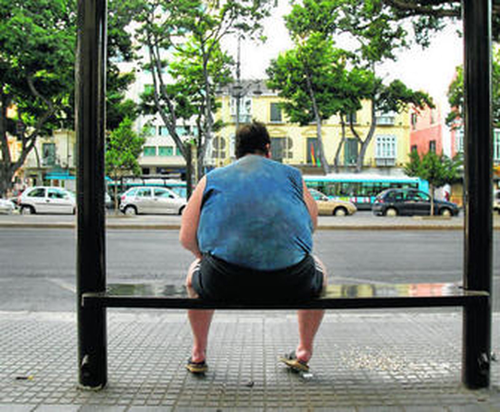 Un hombre obeso espera el autobús.