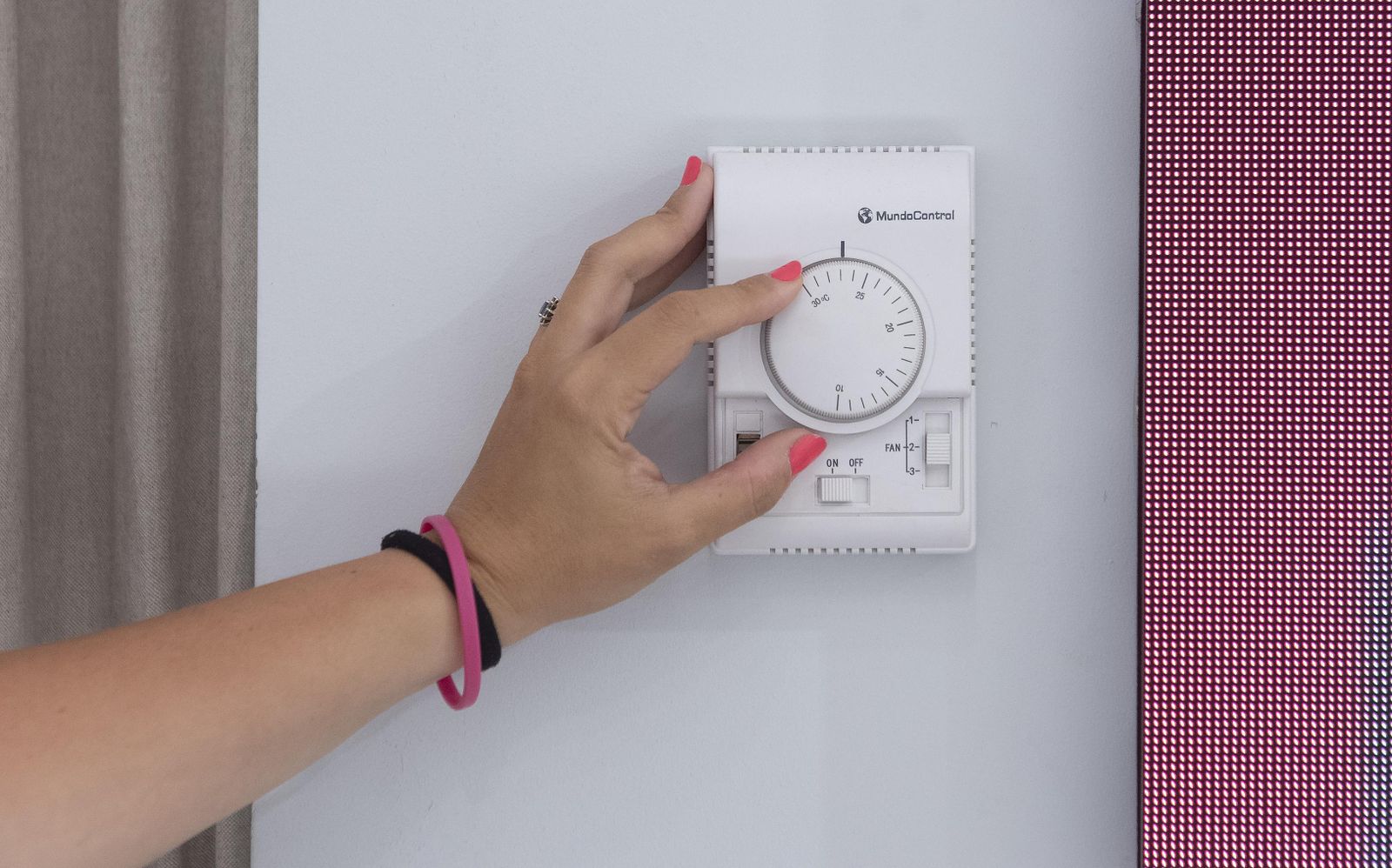 La empleada de un comercio regula la temperatura del aire acondicionado del local.