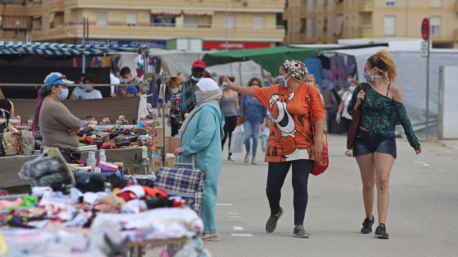 Dos mujeres saludan desde lejos en el mercadillo de Los Barrios, este sábado.