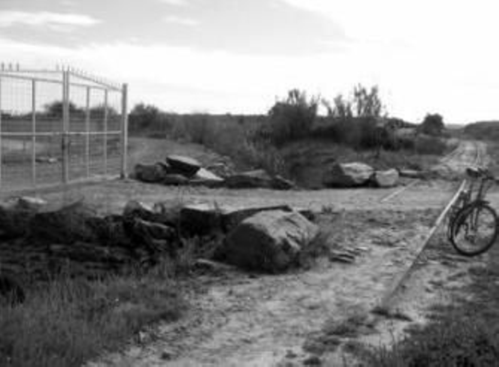 En la imagen las antiguas vías del tren y la puerta que cierra el camino.