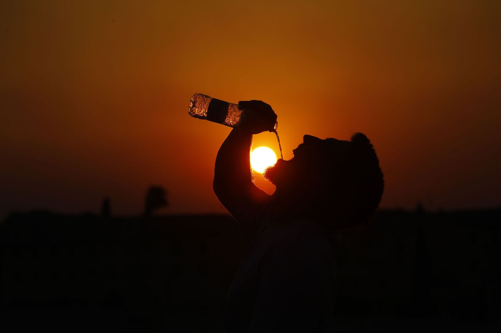 Un hombre bebe agua al atardecer.