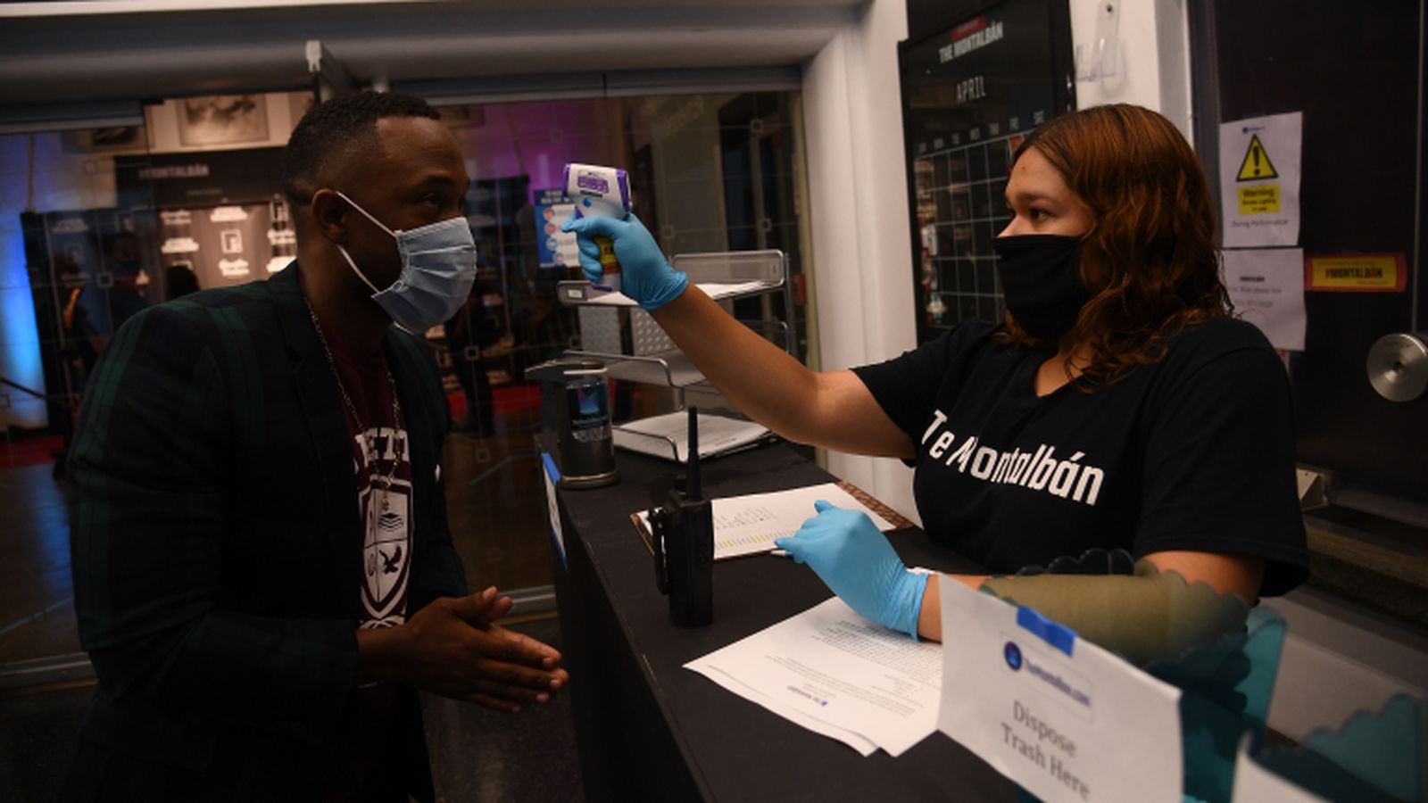 Una empleada del auditorio toma la temperatura a un invitado al estreno.