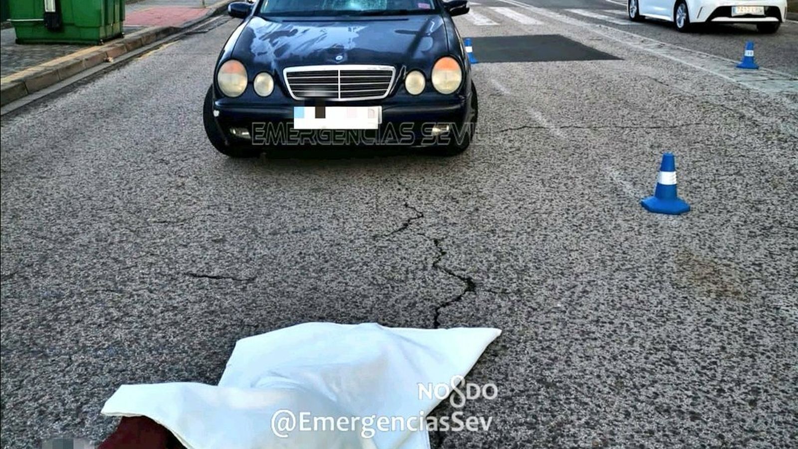El joven herido en el suelo con el vehículo implicado, con el impacto en la luna, al fondo.