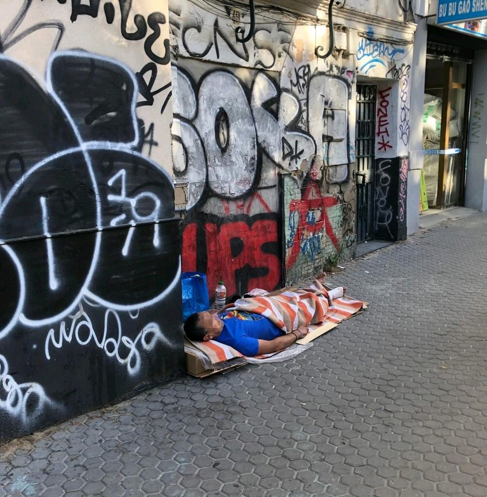 Un indigente duerme en una de las calles del barrio de la Macarena.