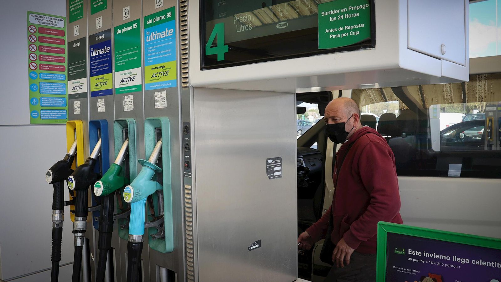 Un conductor junto al surtidor de una estación de servicio.