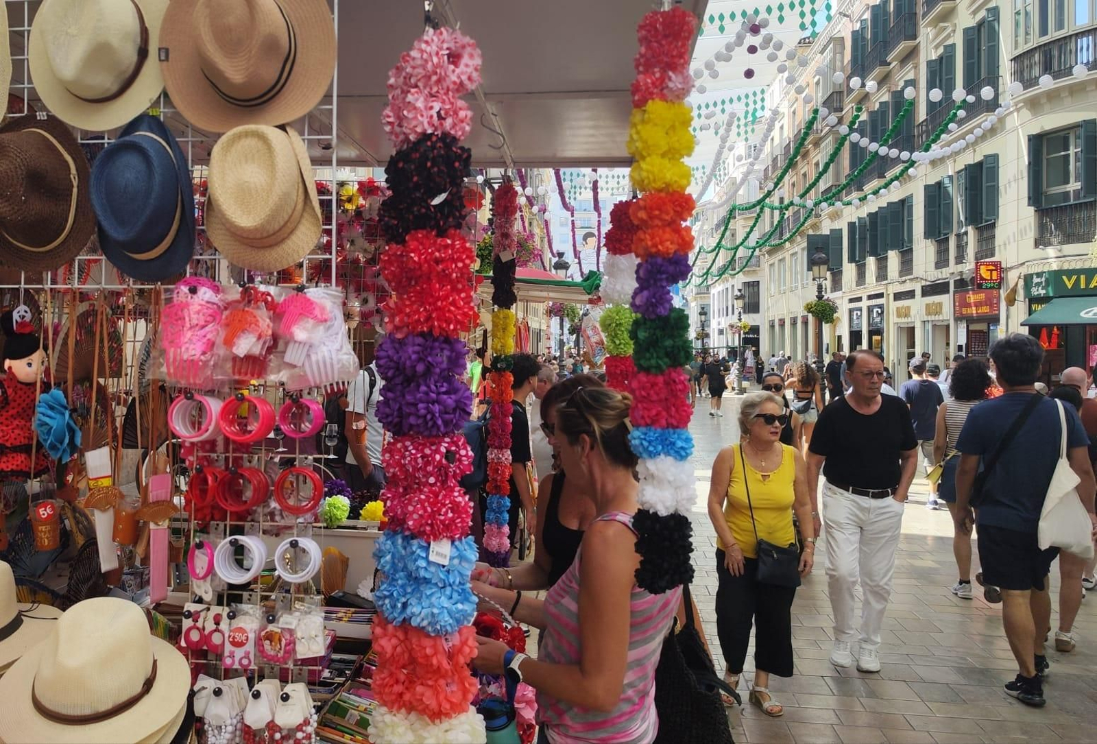 Turistas observando uno de los puestos de Calle Larios.