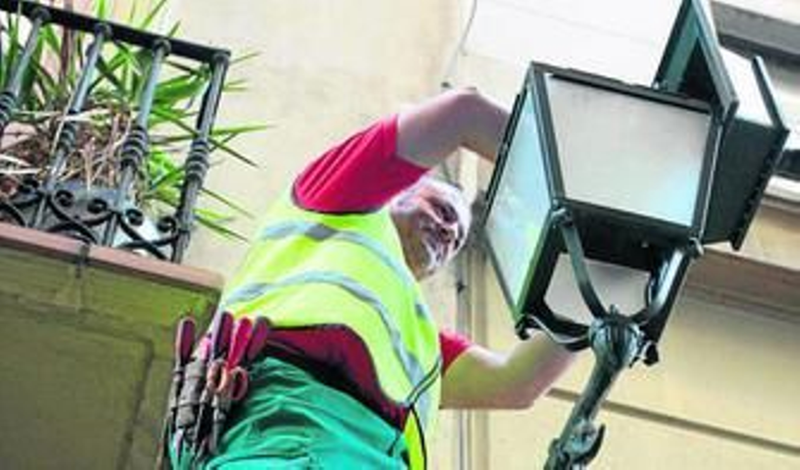 Un operario cambia uno de los faroles para implantar una bombilla led.