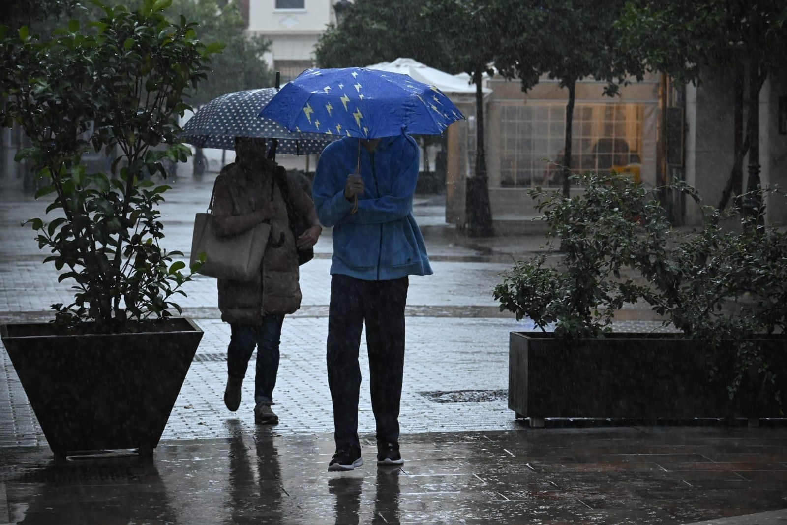 Dos personas con paraguas a primera hora de este lunes en Huelva capital.