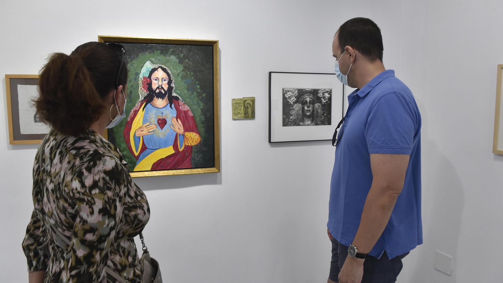 Unos visitantes de la galería observan un 'Sagrado Corazón' de Ocaña y una 'Macarena' de Colita.