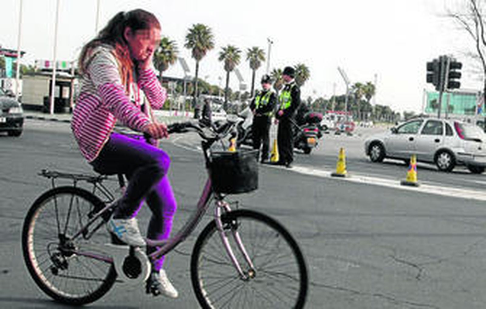 Una ciudadana circula en bicicleta por la zona gibraltareña de la Verja; al fondo, dos 'bobbies'.