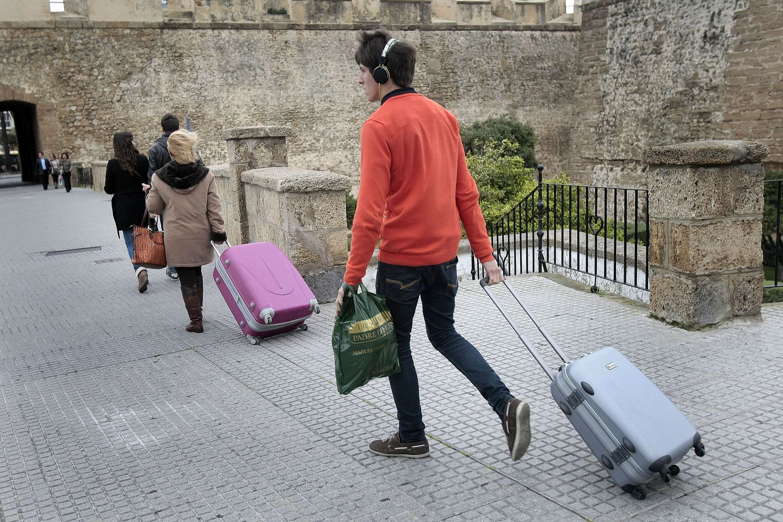 Un joven tira de una maleta pasando por el foso de las Puertas de Tierra.