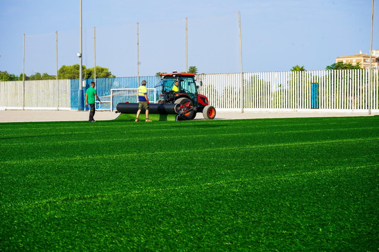 Operarios colocando césped en el campo