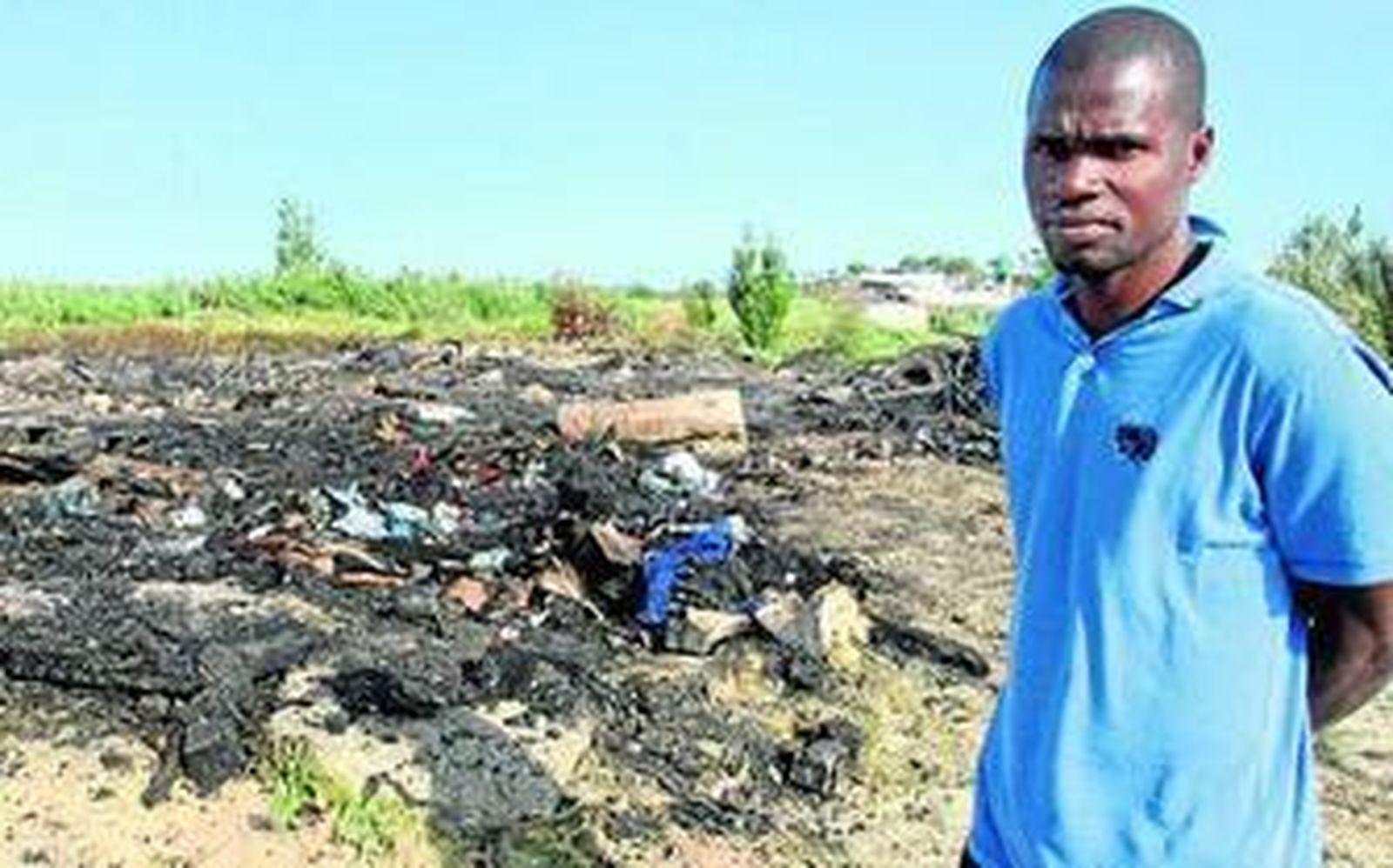 Uno de los moradores del asentamiento, con los restos de las chabolas incendiadas.