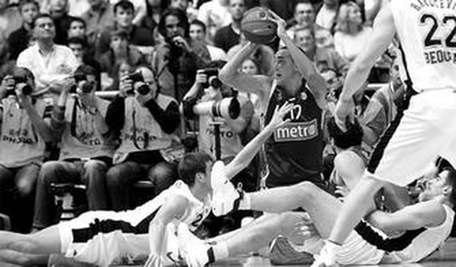 Hervelle busca a quien pasar rodeado por varios rivales y Mumbrú, todos en el suelo.