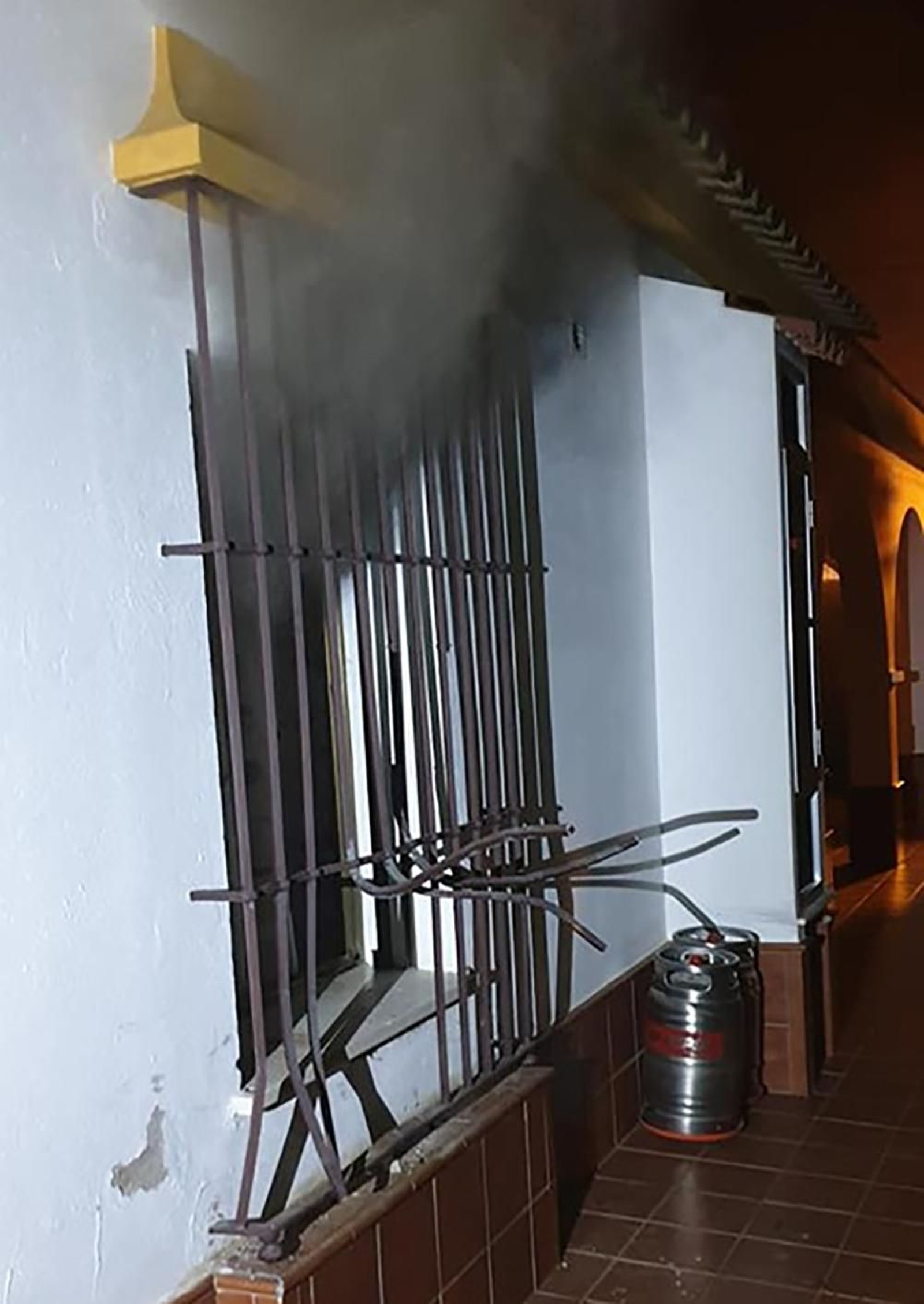 Sale humo por una de las ventanas con los barrotes retorcidos.