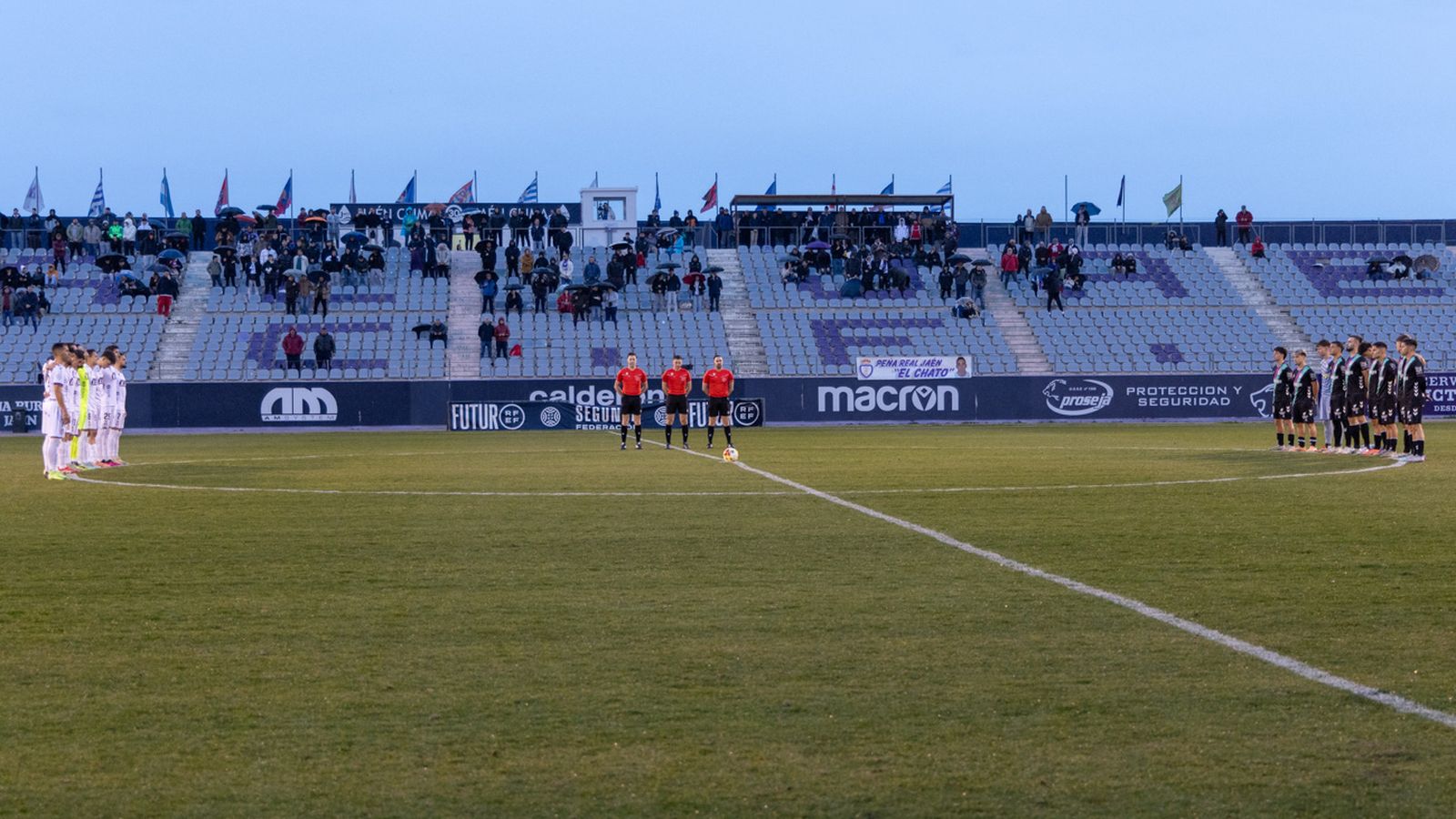 Los jugadores de ambos equipos y el trío arbitral durante el minuto de silencio.