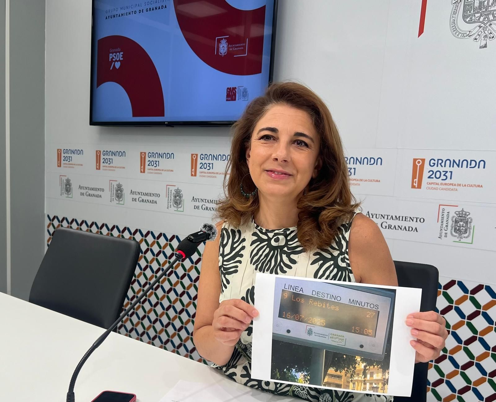 Raquel Ruz muestra un indicador de autobuses con 27 minutos de retraso en la Línea 9