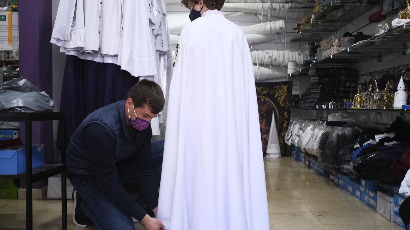 José Manuel Cabello ajusta una túnica a un joven nazareno en su tienda.