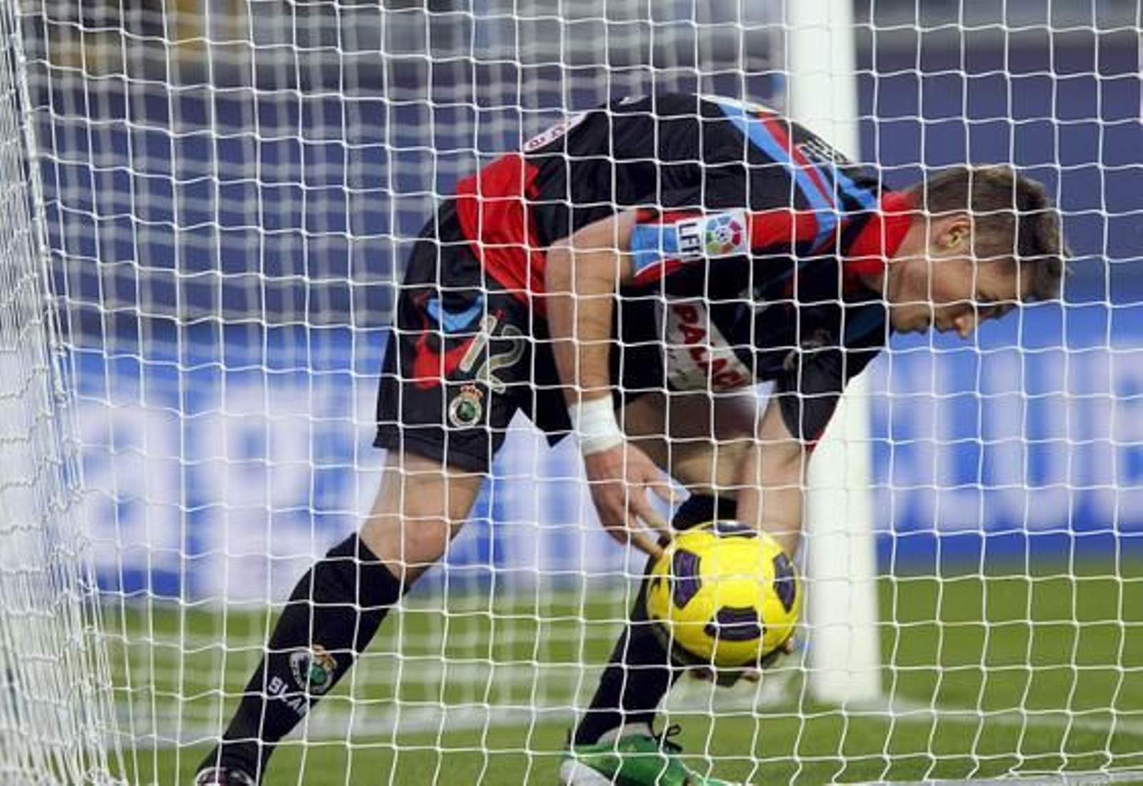 El delantero del Racing Nils Markus Rosenberg recoge el balón de la portería del Málaga tras marcar el primer y único gol del equipo.

Foto: Jorge Zapata/EFE