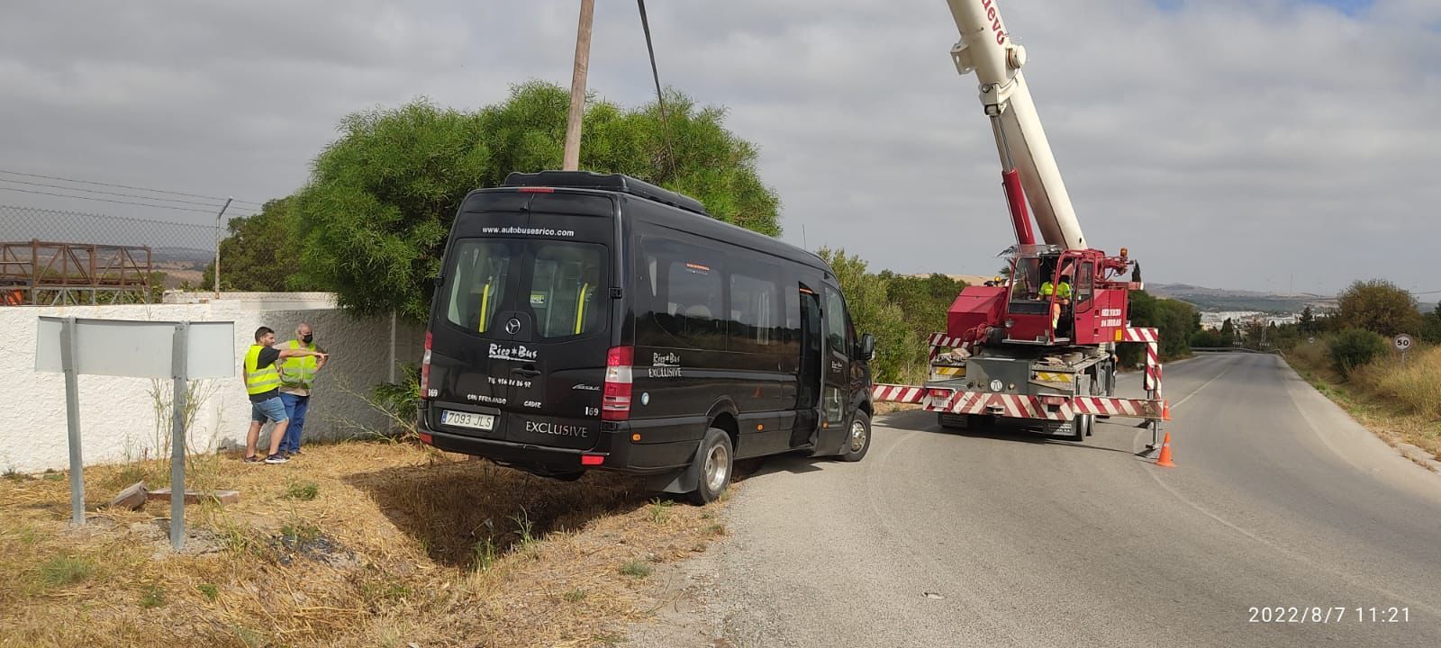 Una grúa retira el minibús accidentado.