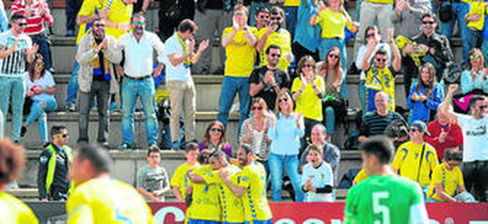Los jugadores del Cádiz celebran el gol que les daba ventaja mientras los aficionados aplauden en la grada destinada a los seguidores amarillos.