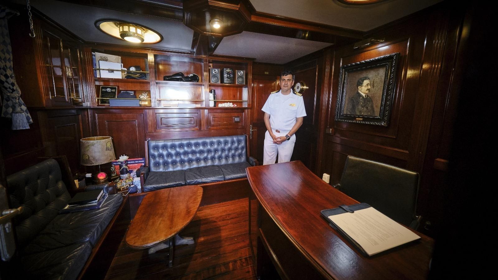 El comandante del buque en su despacho junto a una foto del Capitán Miranda.