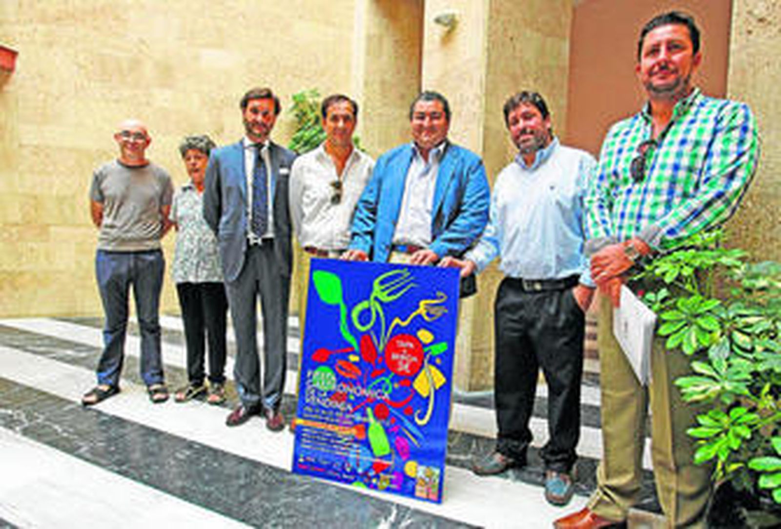 Organizadores de la Fiesta Gastronómica mostrando el cartel de este evento incluido en las Fiestas de la Vendimia.