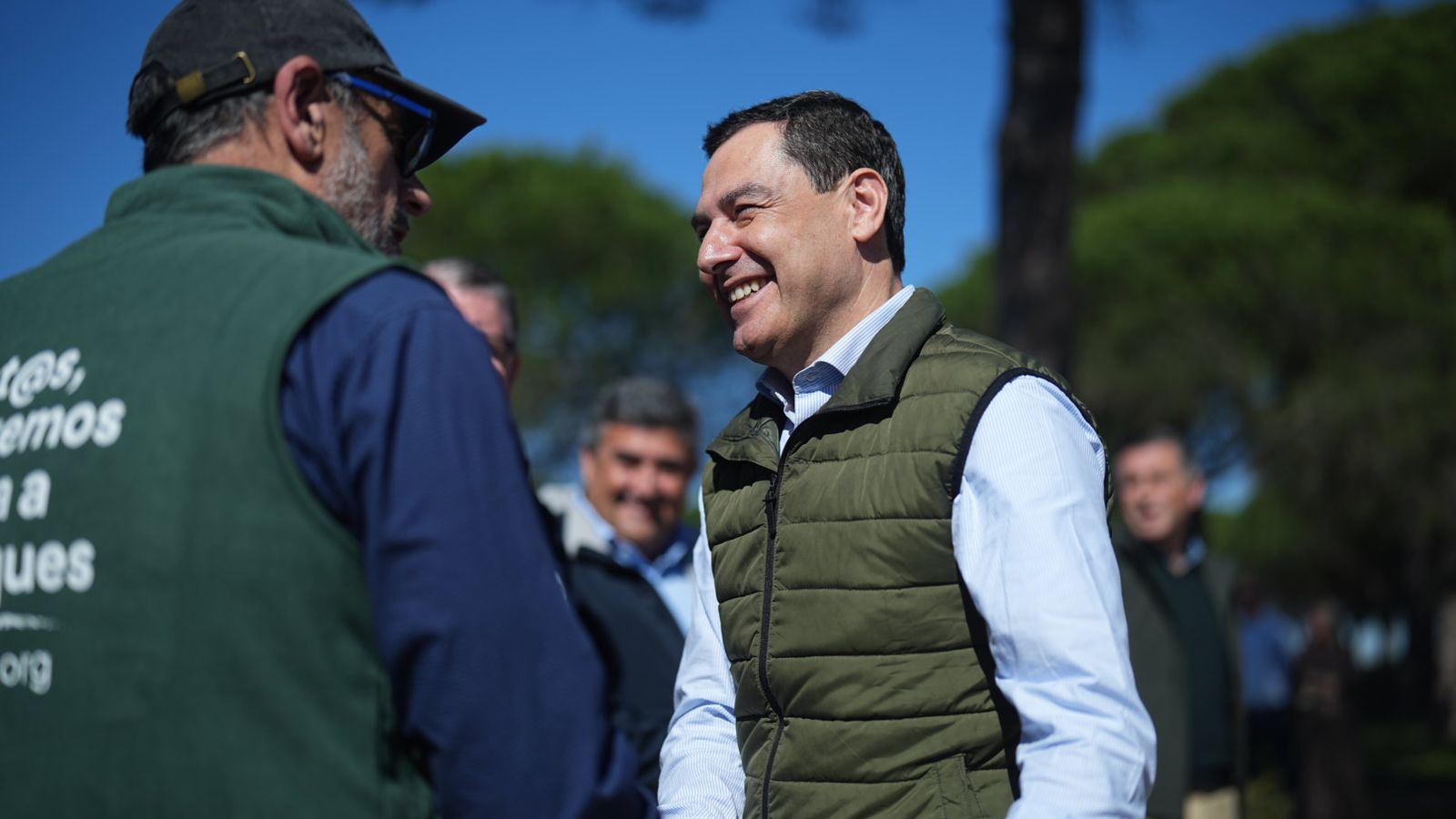 Juanma Moreno conversa con uno de los trabajadores que presta su servicio en la plantación de árboles en el paraje de 'Las Peñuelas'.