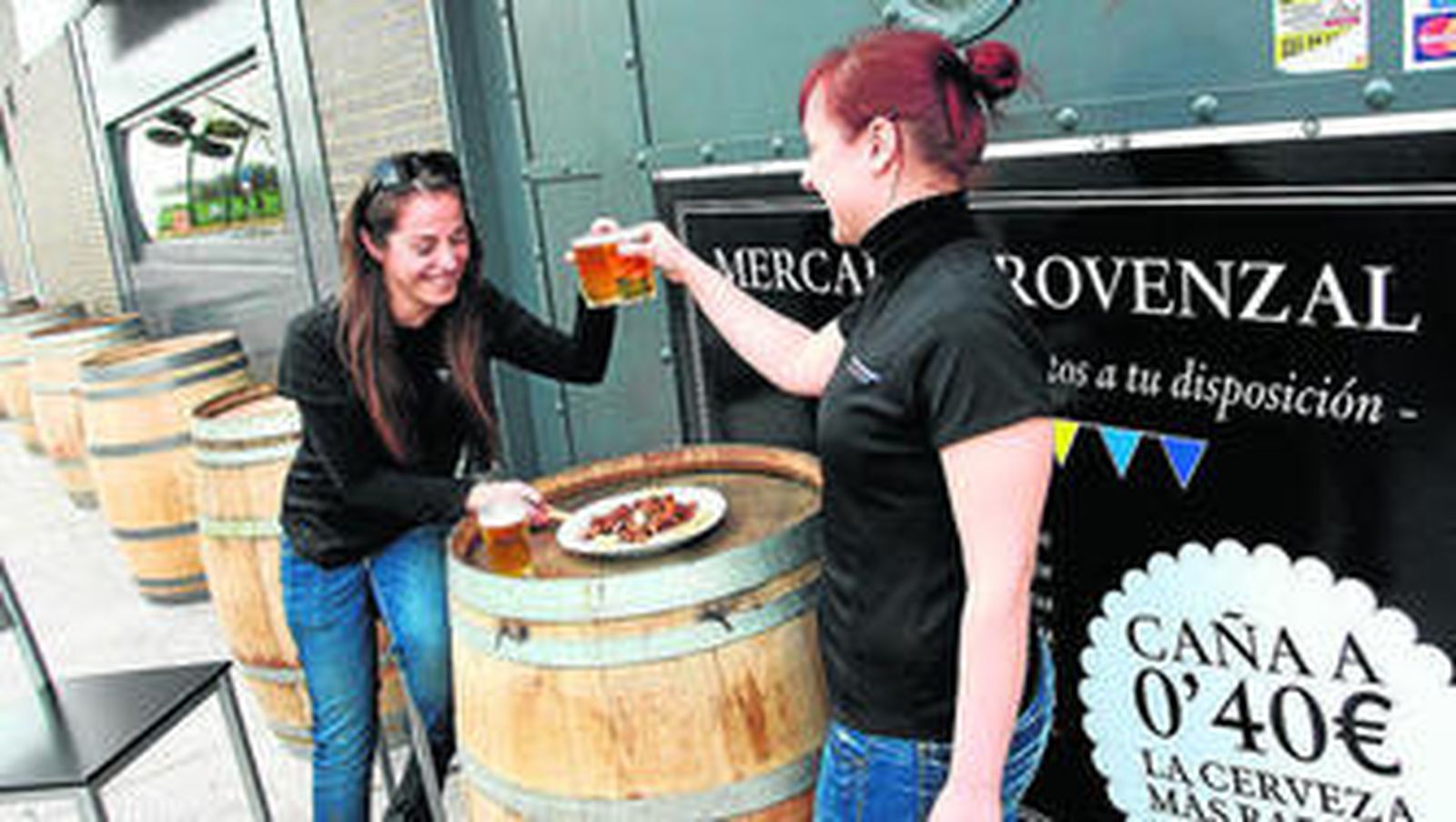 Dos jóvenes toman un aperitivo en la puerta del Mercado Provenzal de Los Bermejales.