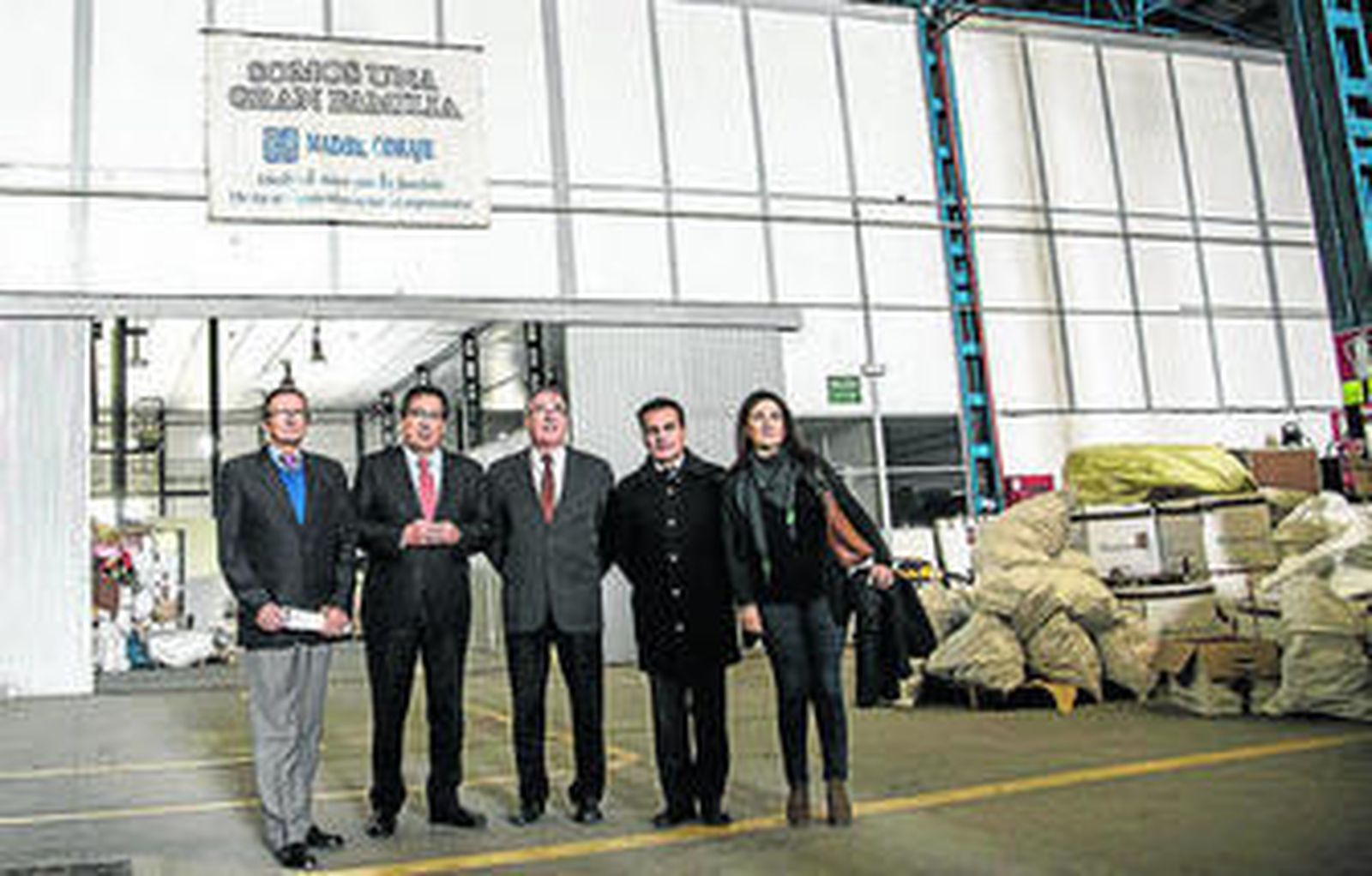 Representantes de Cajasol, 'la Caixa' y 'Madre Coraje' posan en la nave de la oenegé.