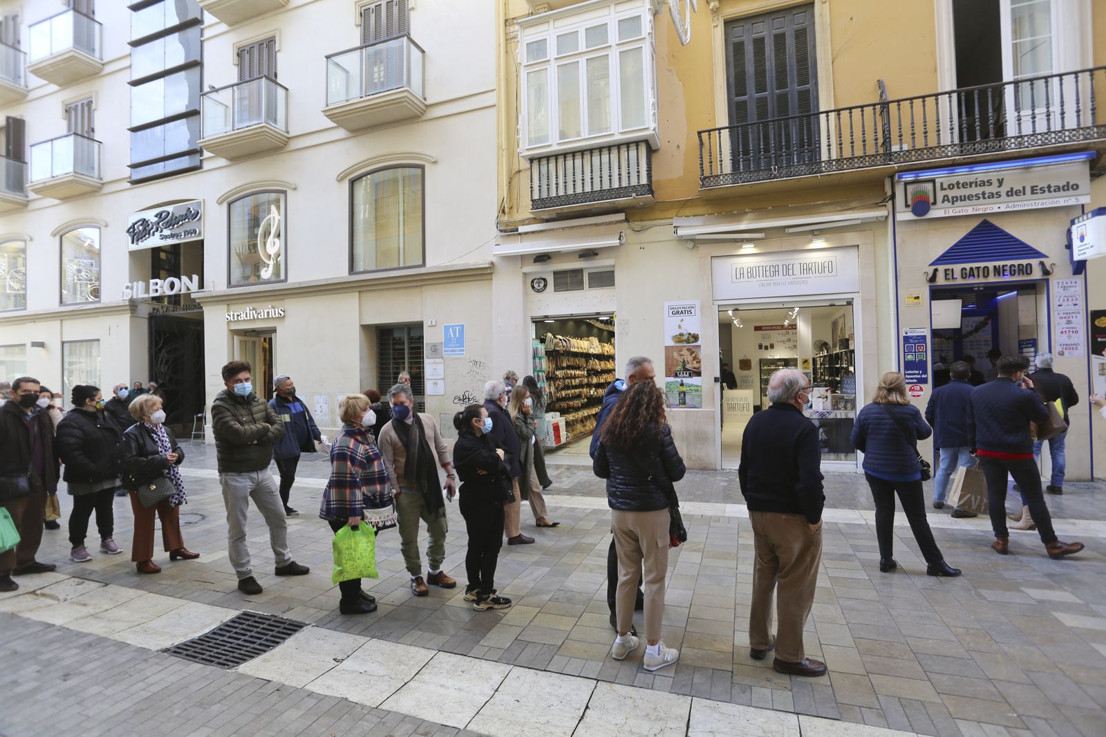 Vecinos y turistas esperan su turno a las puertas de una administración para comprar lotería.