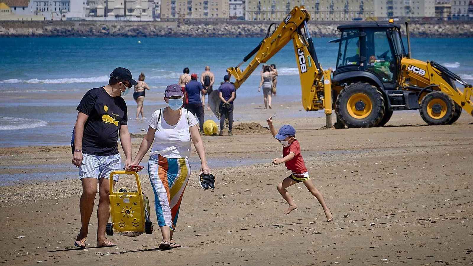 Una familia pasea por la playa de Cádiz.