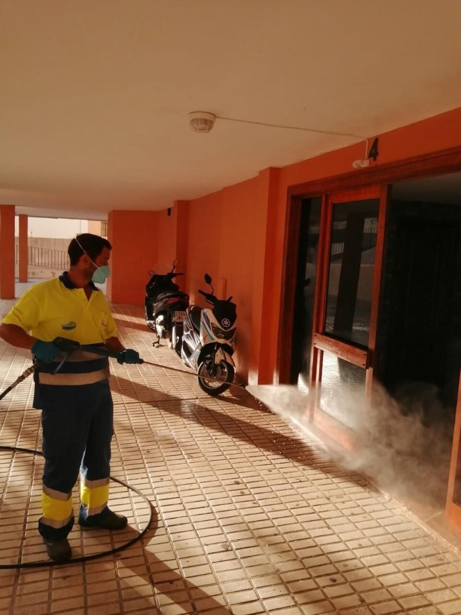 Tareas de desinfección en la entrada de un bloque de pisos de Chiclana.