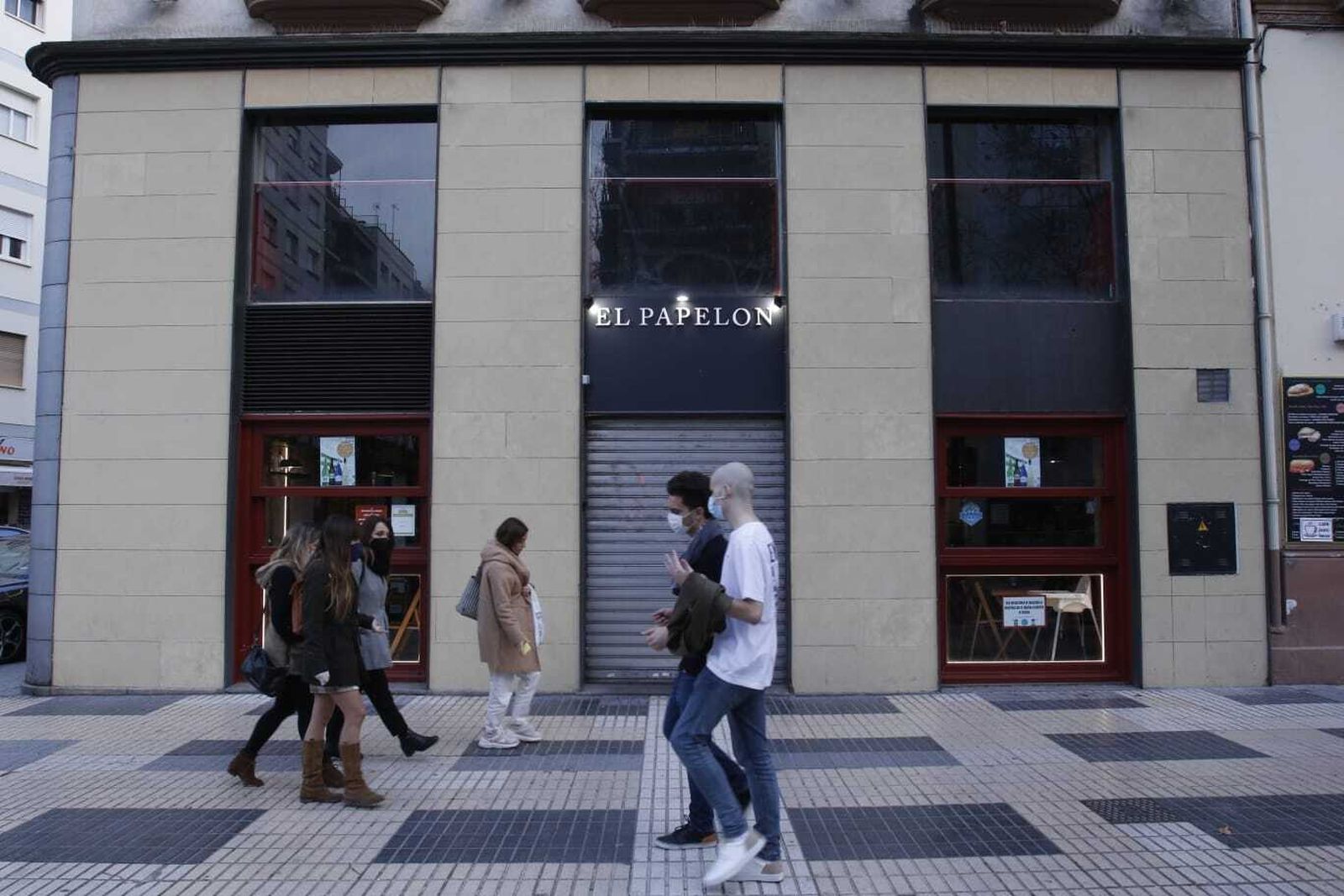 Varias personas pasan por la entrada del negocio.