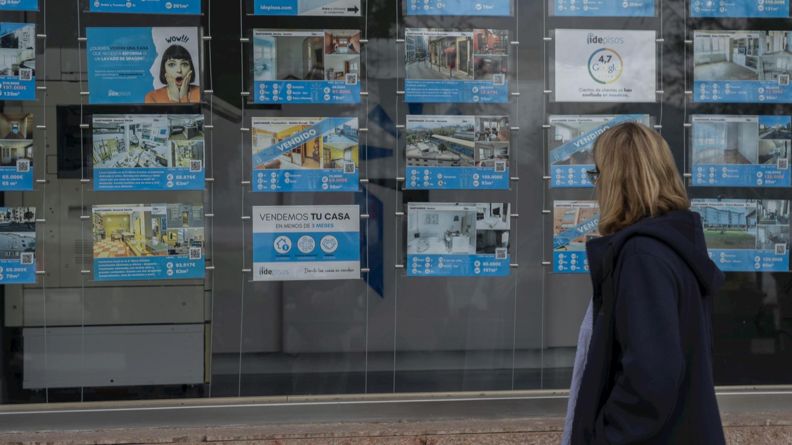 Una mujer pasa frente al escaparate de una inmobiliaria