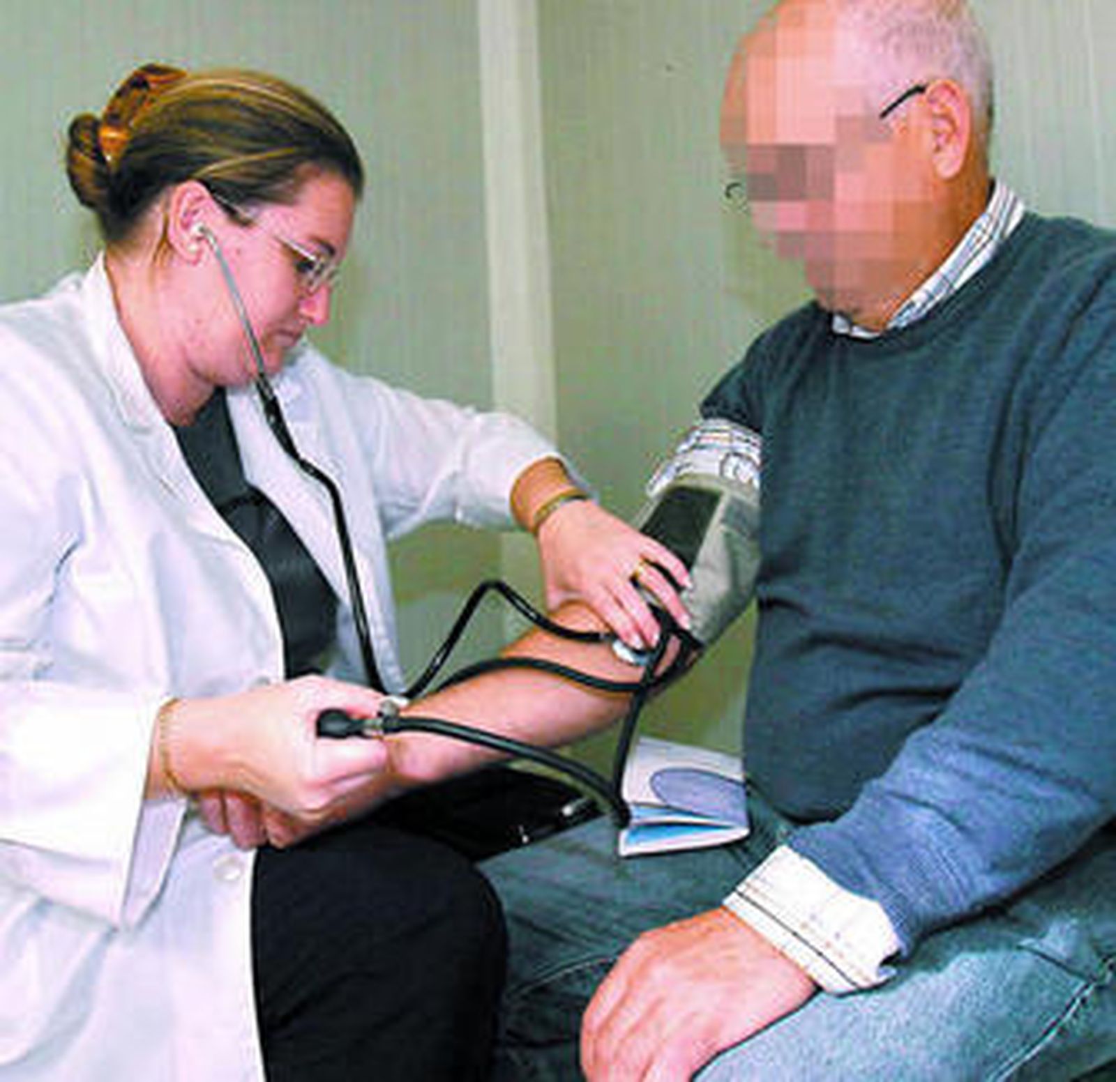 Una doctora le mide la tensión arterial a un paciente.