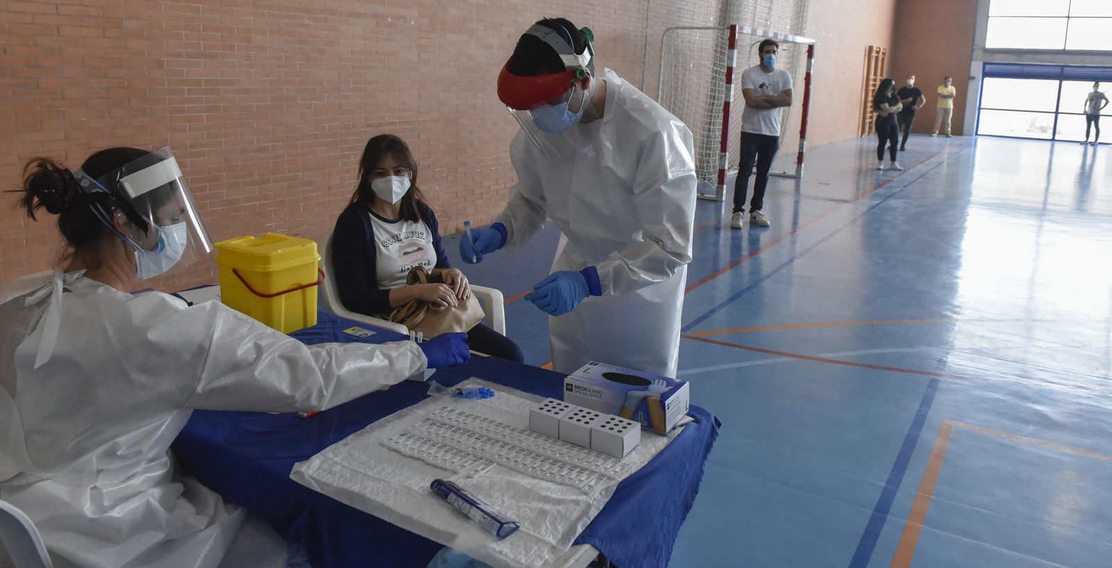 Dos sanitarios preparan muestras en Écija mientras una vecina espera su turno.